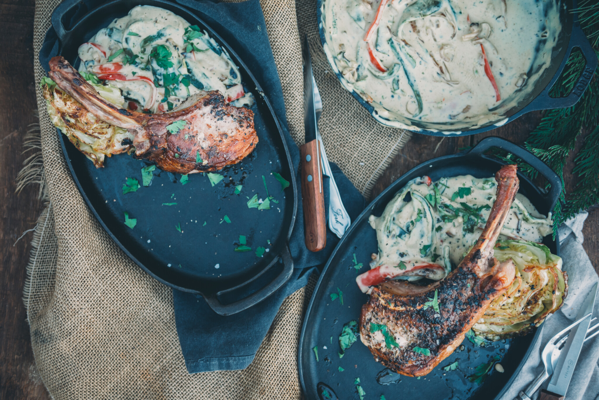 Pork chops on platters with rajas con crema on the side and in a large skillet for serving. 