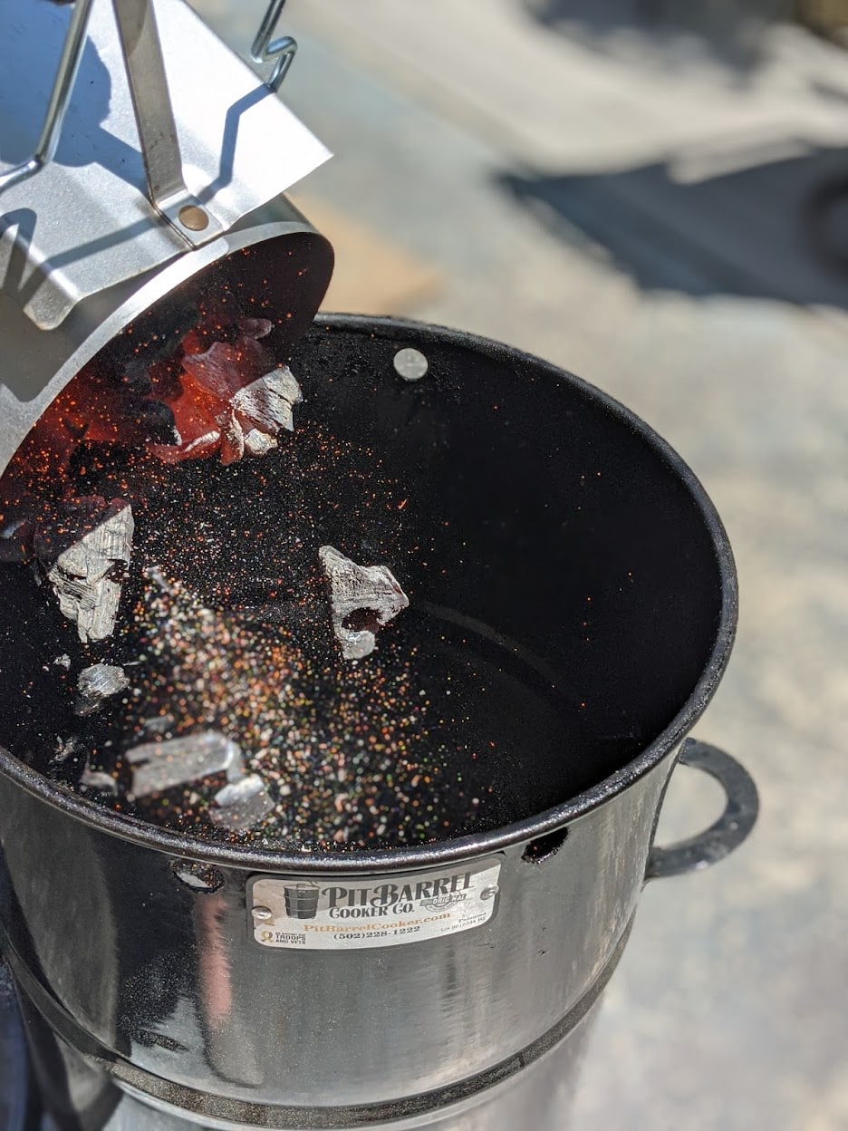 charcoal being poured into a pit barrel cooker