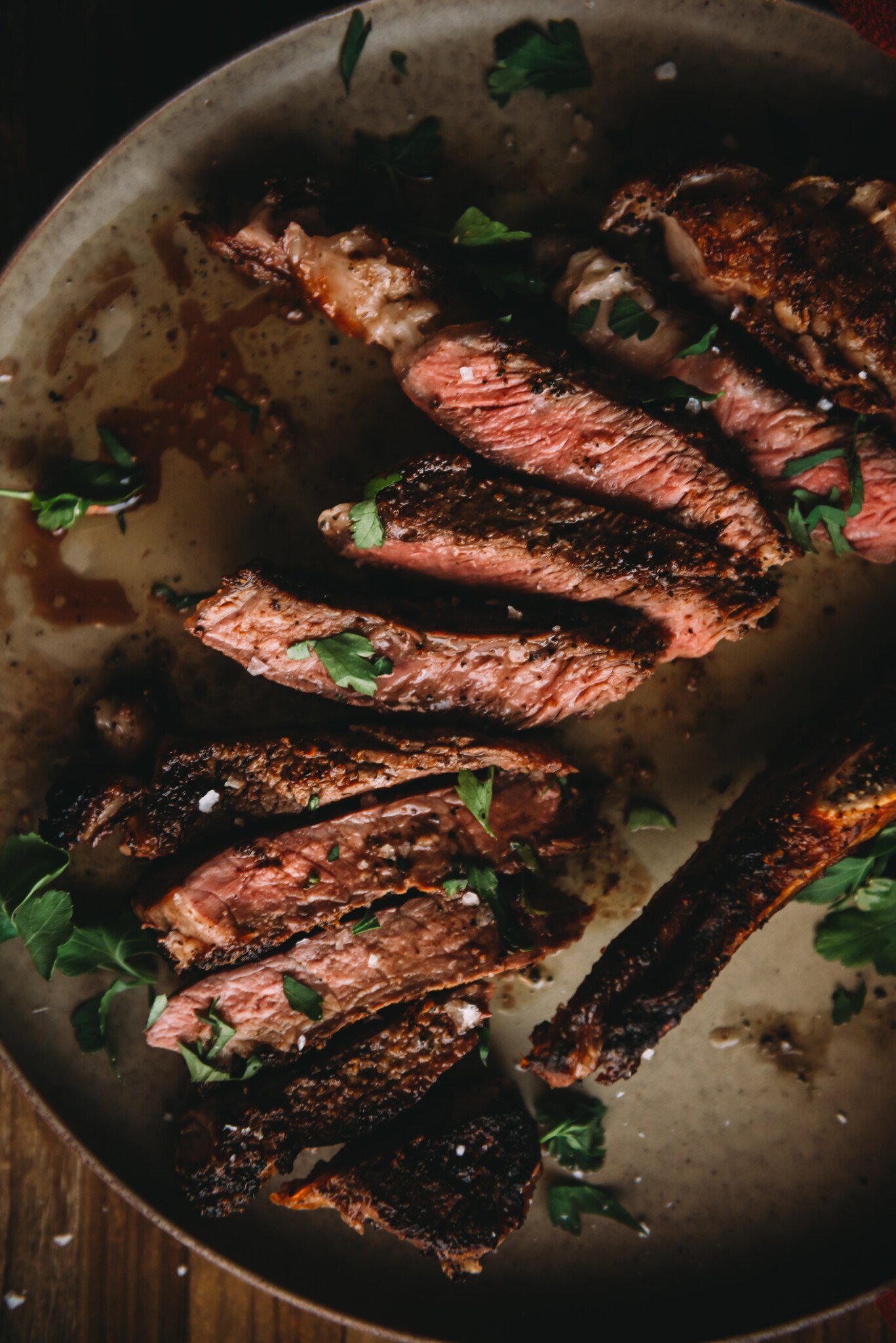 Close up of steak sliced and resting on a plate of juices and melted butter.