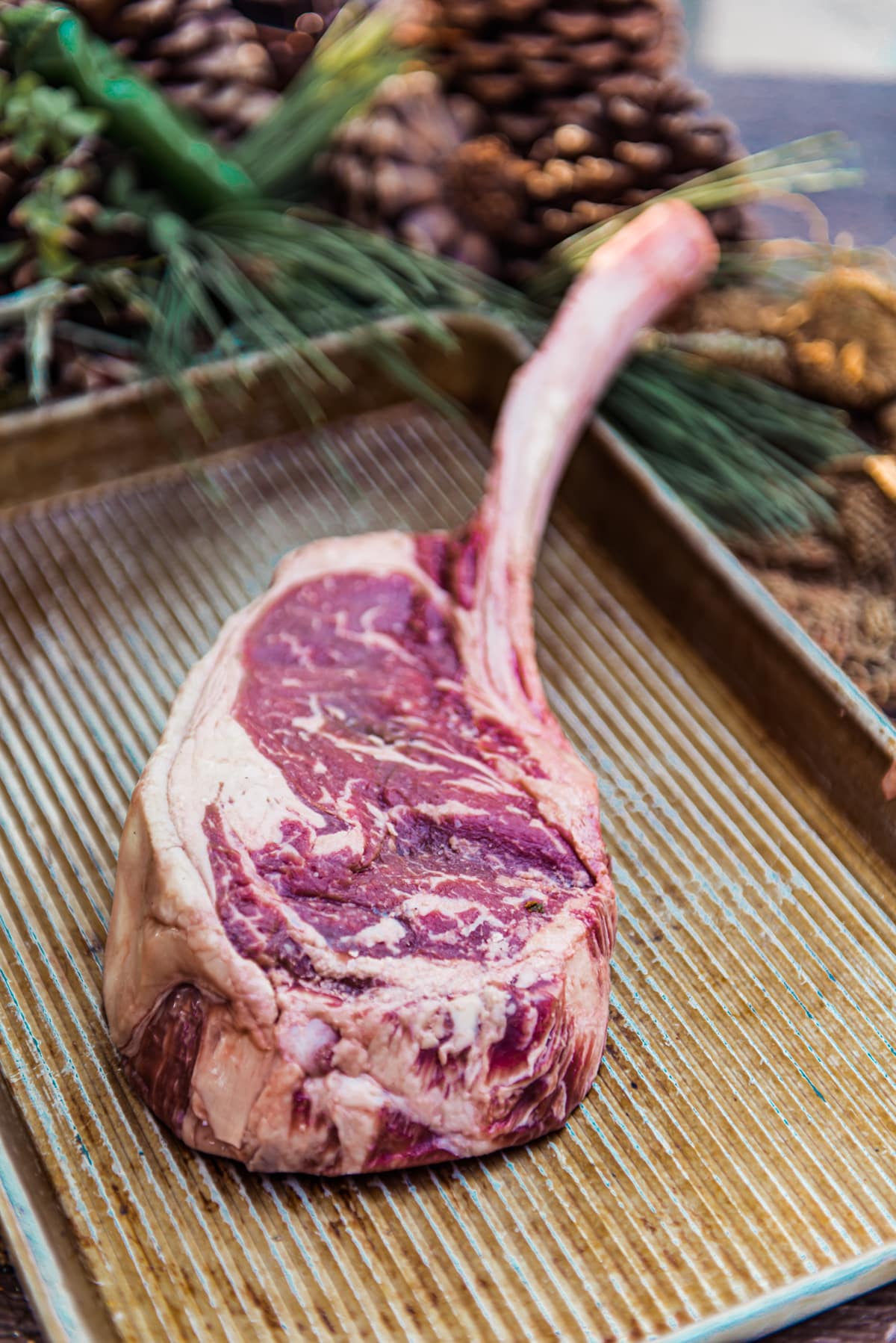 raw tomahawk steak, a big ribeye steak with the untrimmed rib bone on a metal sheet. 