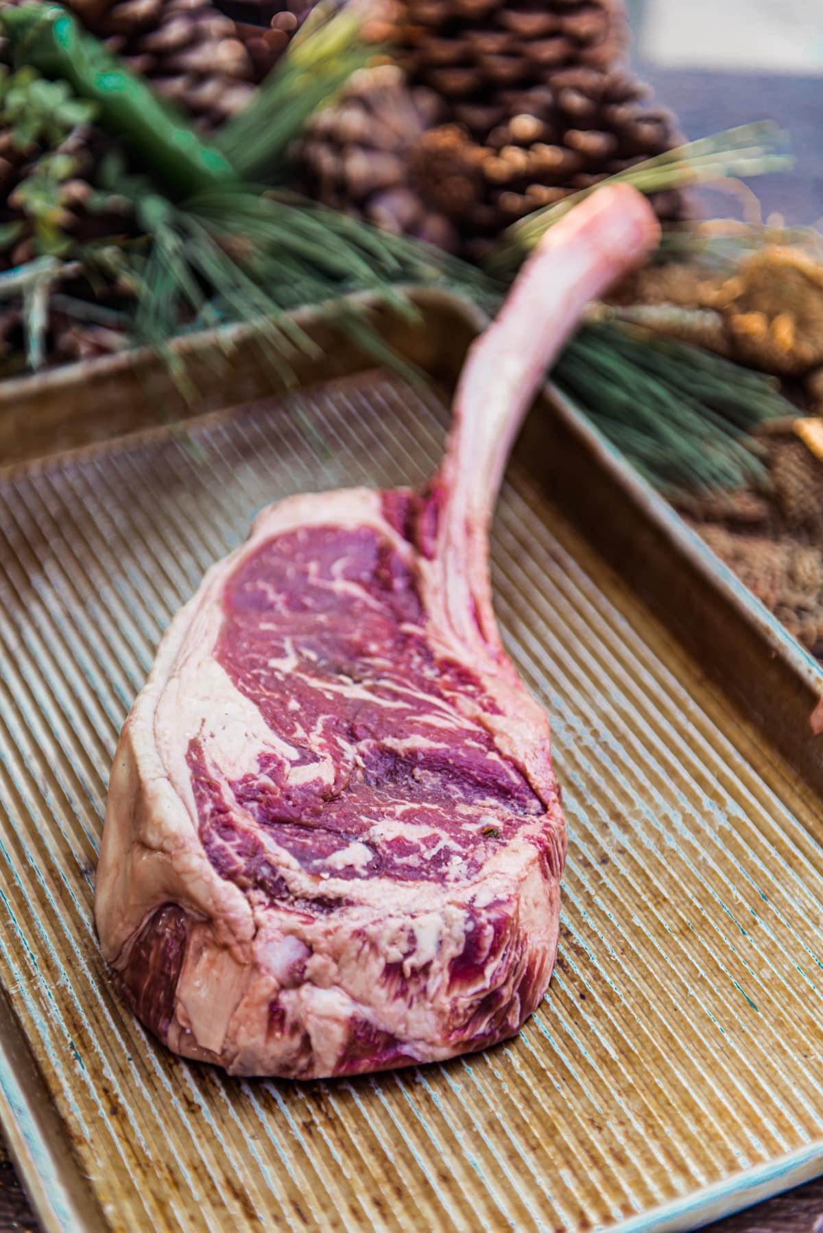 raw tomahawk steak, a big ribeye steak with the untrimmed rib bone on a metal sheet 