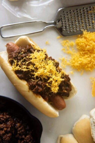 Flat lay photo of Chili Cheese Dog with Spicy Southwest Hot Dog Chili laid on a white surface.