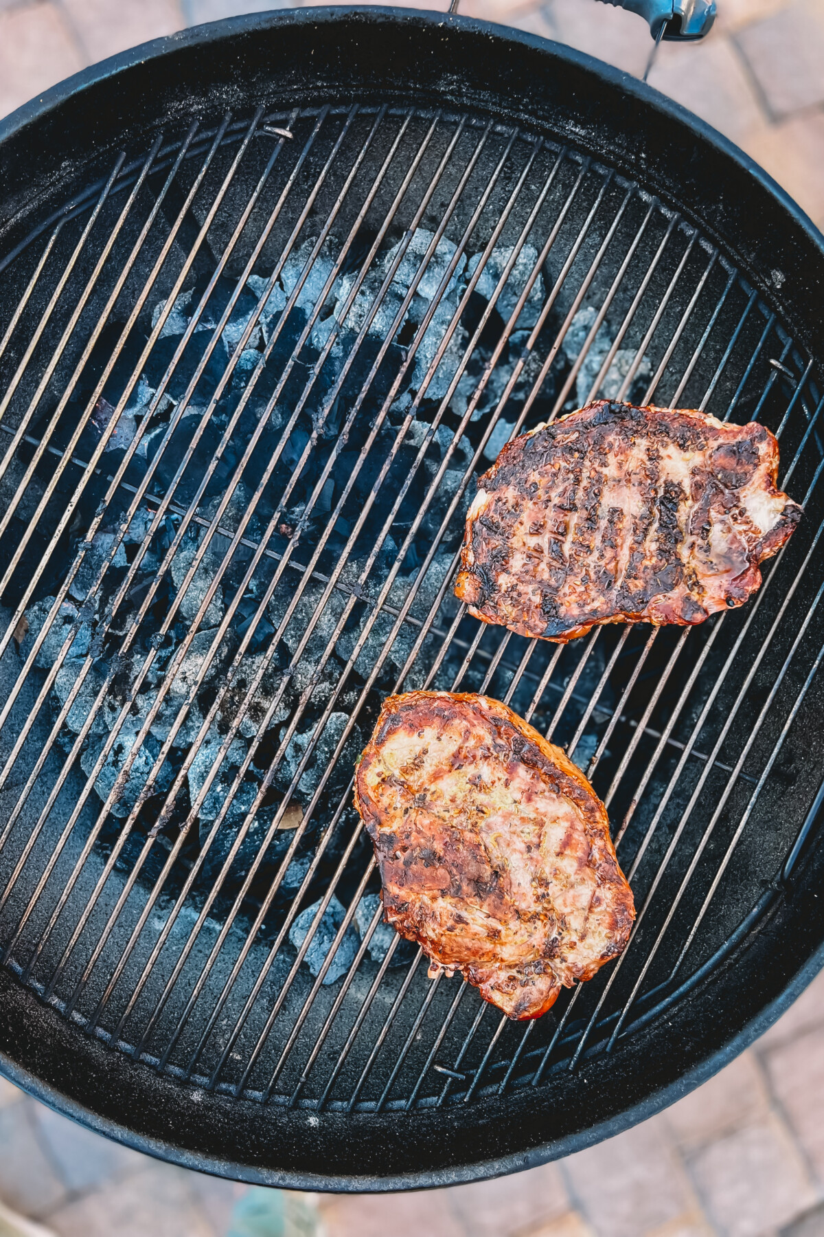 2 pork chops with grill marks and a little char over charcoal grill