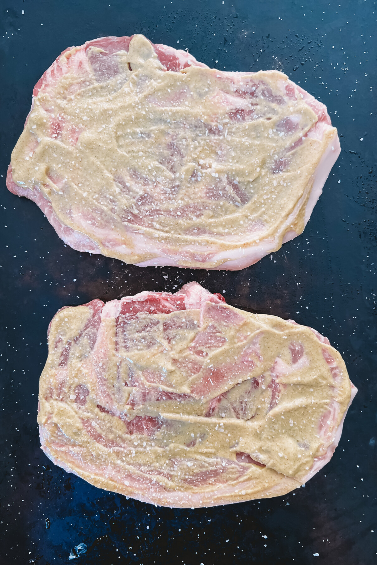 2 bone-in pork steaks slathered in mustard sauce.