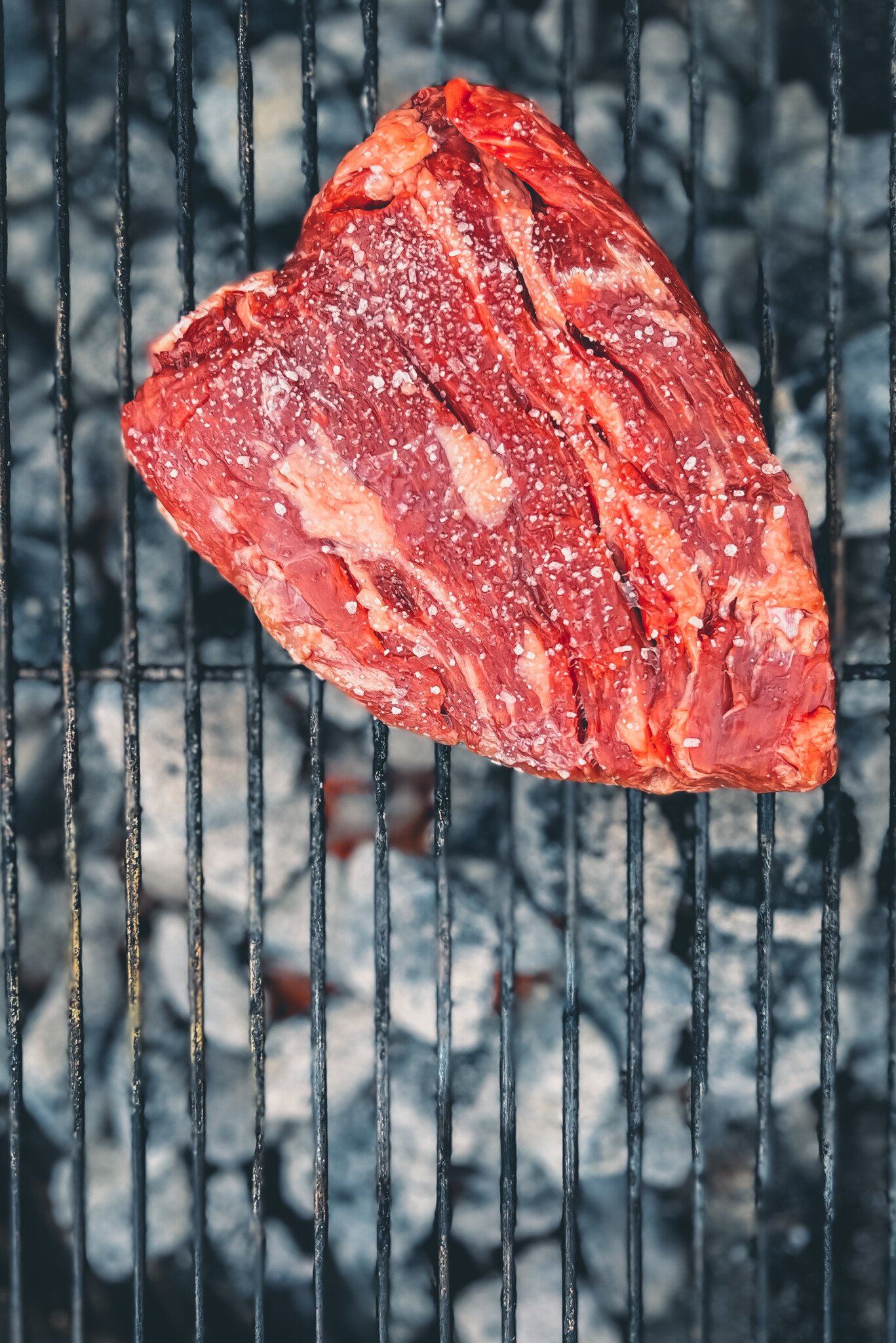 Bavette steak hitting the grill; Seasoned with salt and over the goals. 