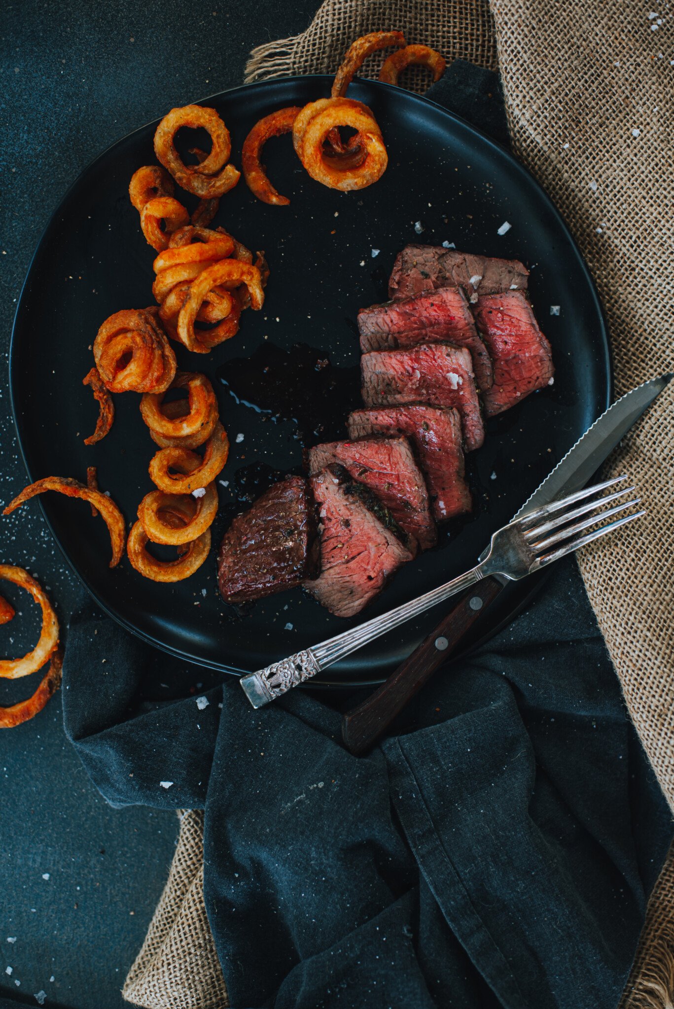 Sliced sirloin filet on a back plate with fries. 