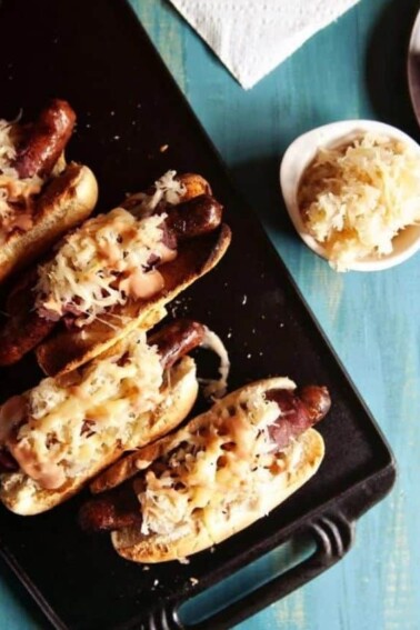Flat lay photo of Reuben Hot Dogs in a black tray.