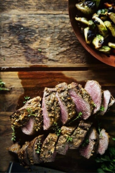 Flat lay photo of Walnut Crusted Grilled Beef Tenderloins with Charred Brussels on a wooden surface.