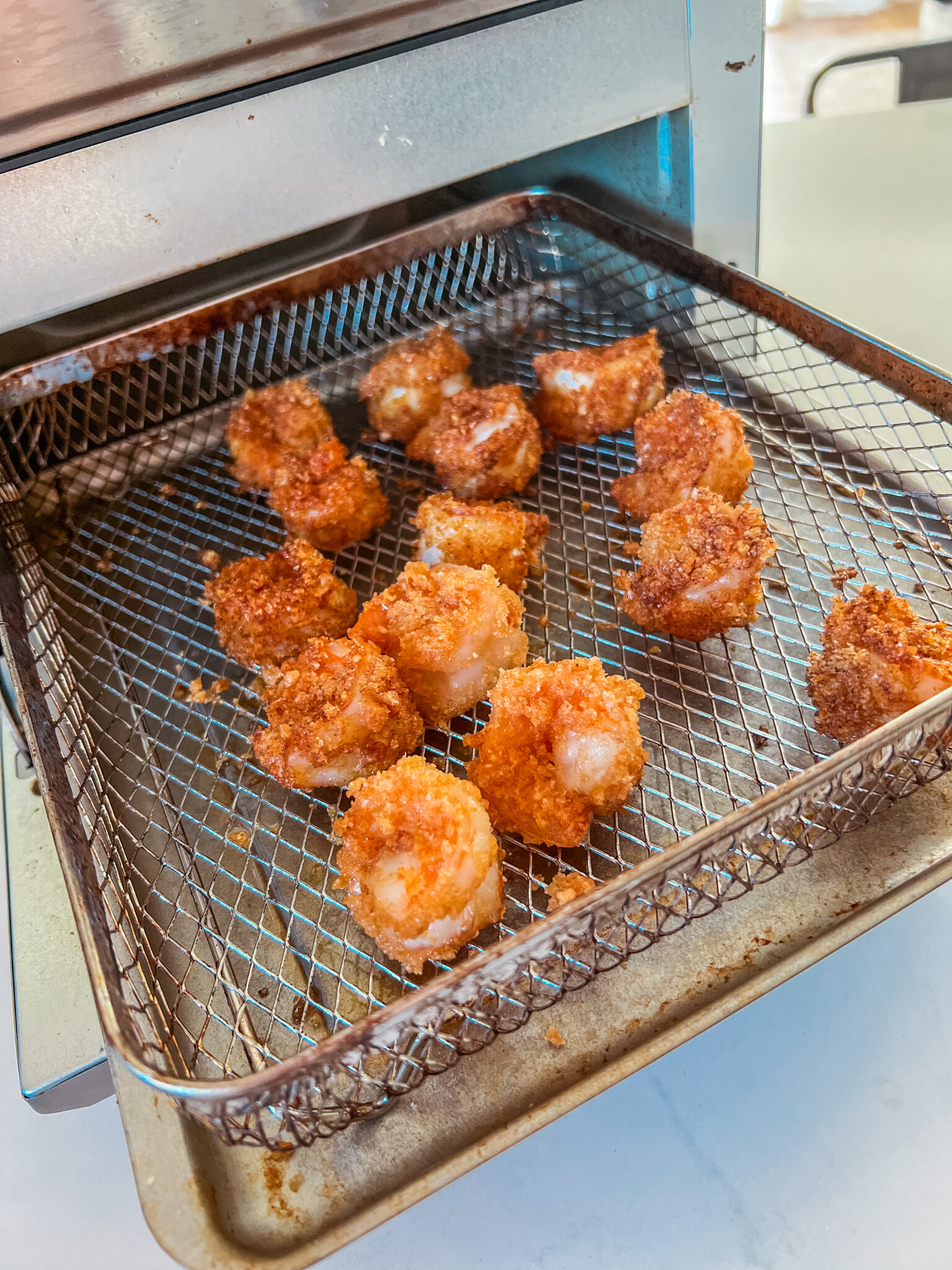 Shrimp that have just been cooked in the basket of an air fryer. 