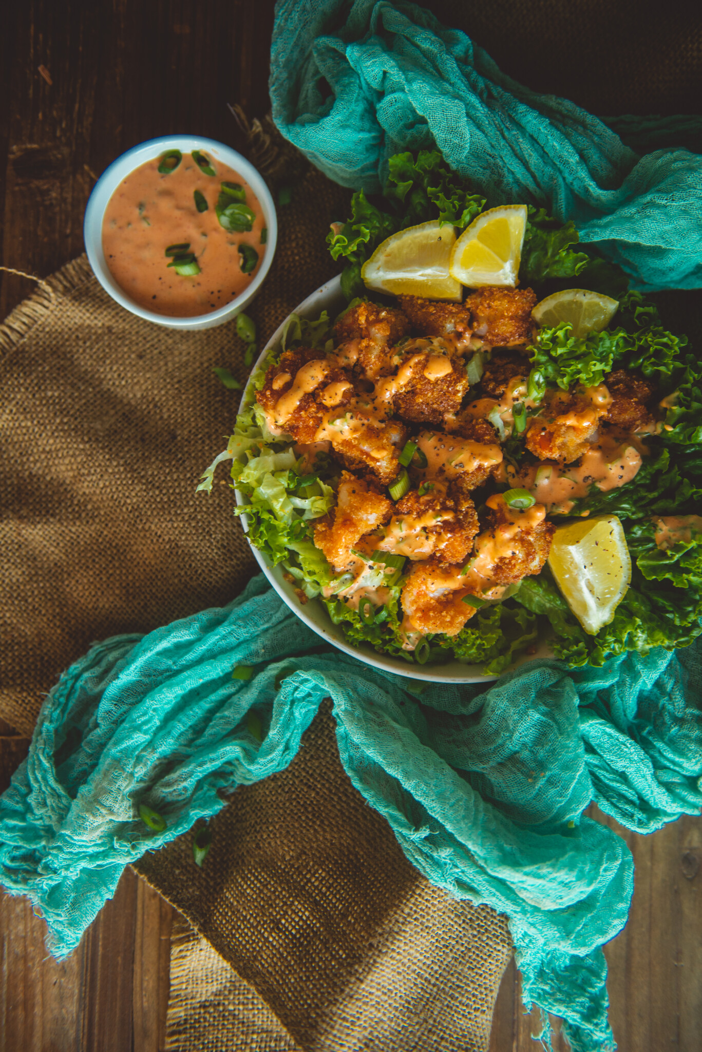 Overhead of bowl filled with air fryer shrimp coated in sauce over lettuce. 