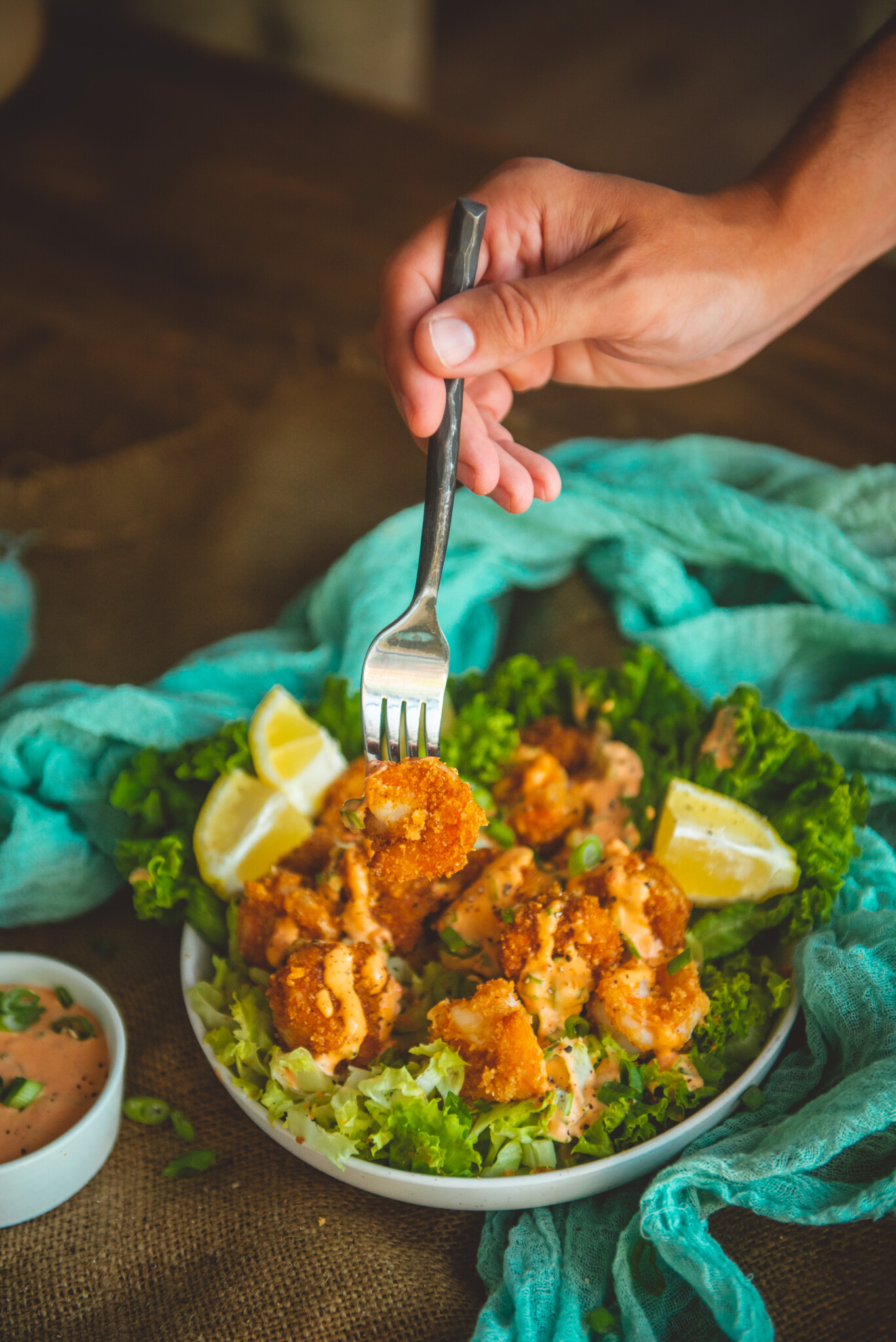 hand with fork spearing a crispy pork panko coated shrimp over a bowl of more bang bang shrimp. 