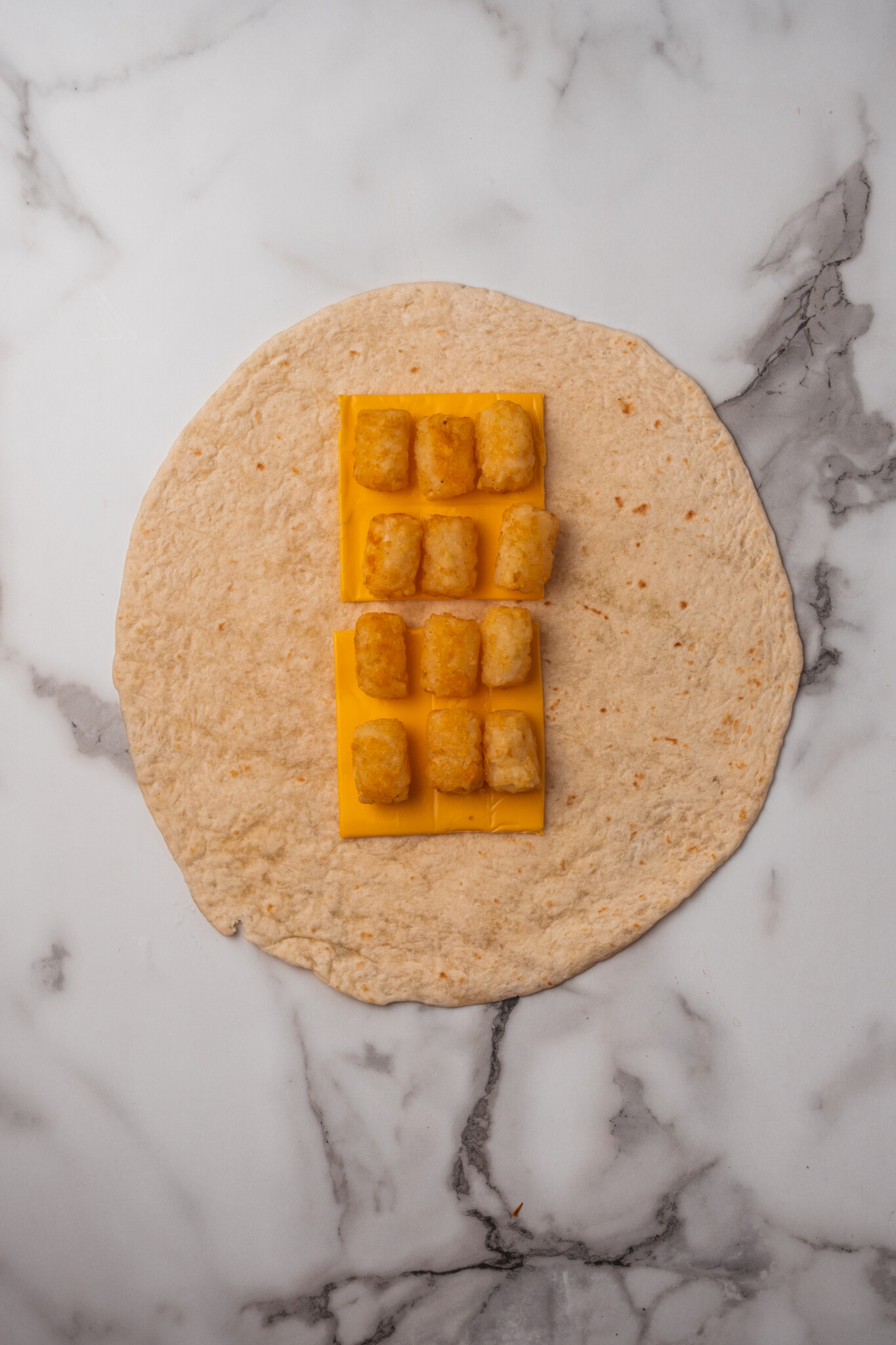 adding tater tots on top of the cheese on the tortilla