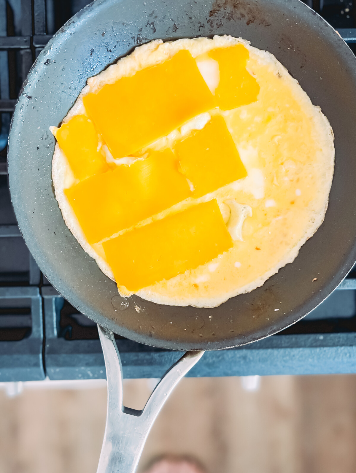 Cheese being laid over eggs in a skillet to make an omelet.