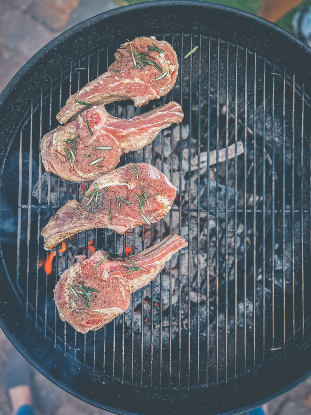 Veal chops over direct heat on a grill.