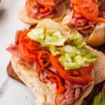 Italian hoagies topped with sliced tomato and lettuce.