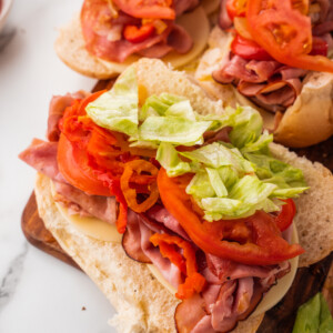 Italian hoagies topped with sliced tomato and lettuce.