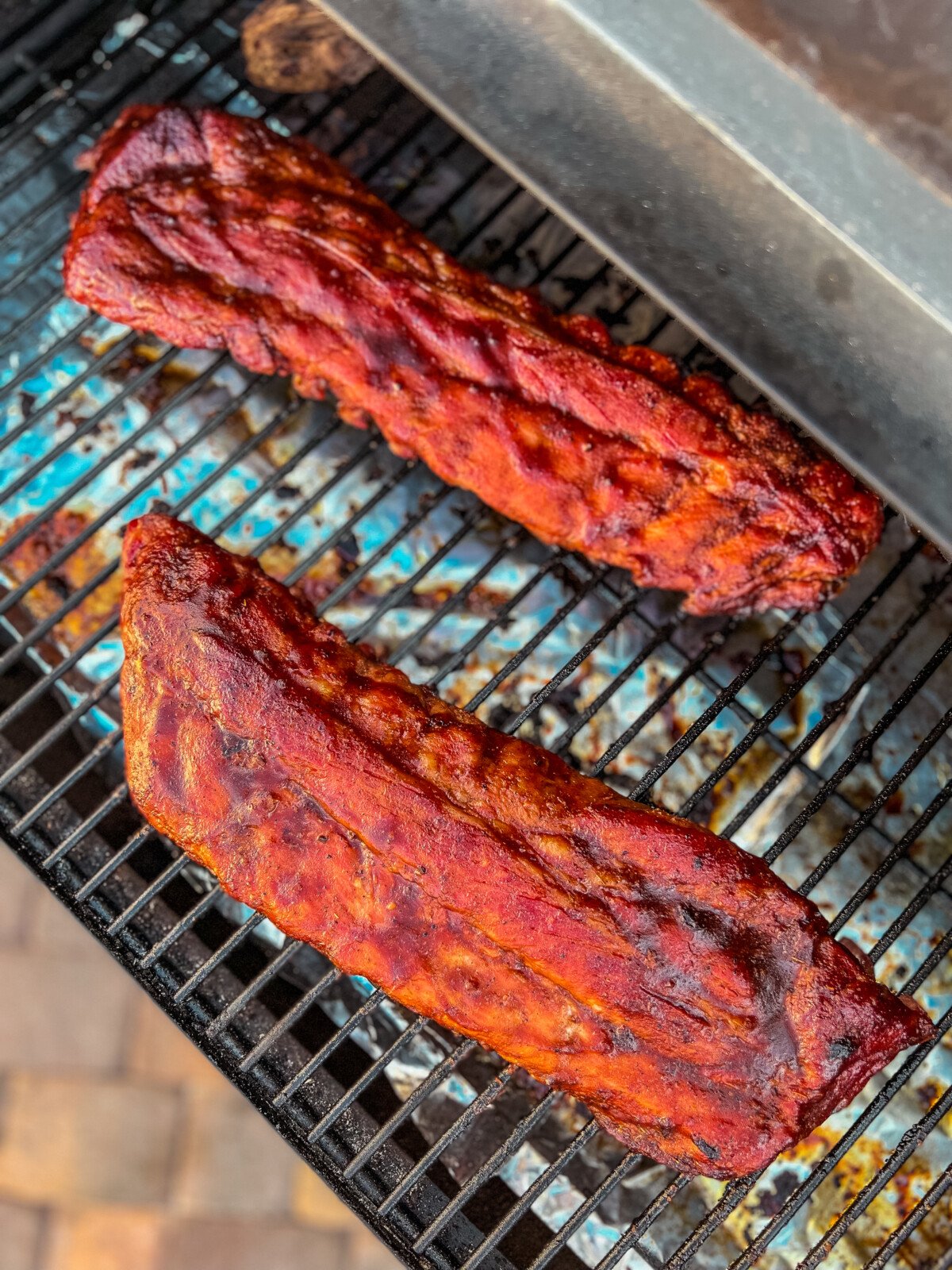 2 racks of ribs brushed with barbecue sauce on a Traeger grill.