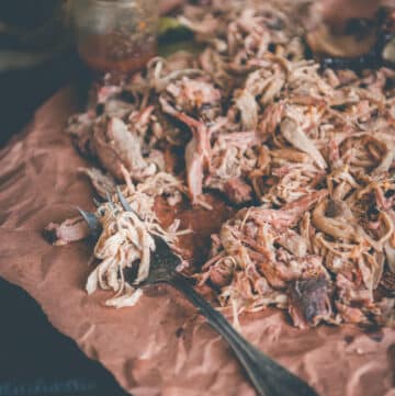 shredded pork on butcher paper with fork and sauce in background.