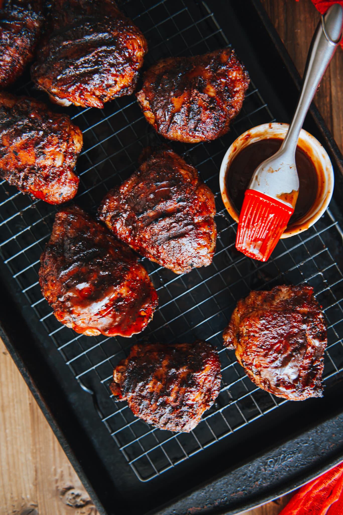 Smoked chicken thighs on a wire rack brushed with bbq sauce. 