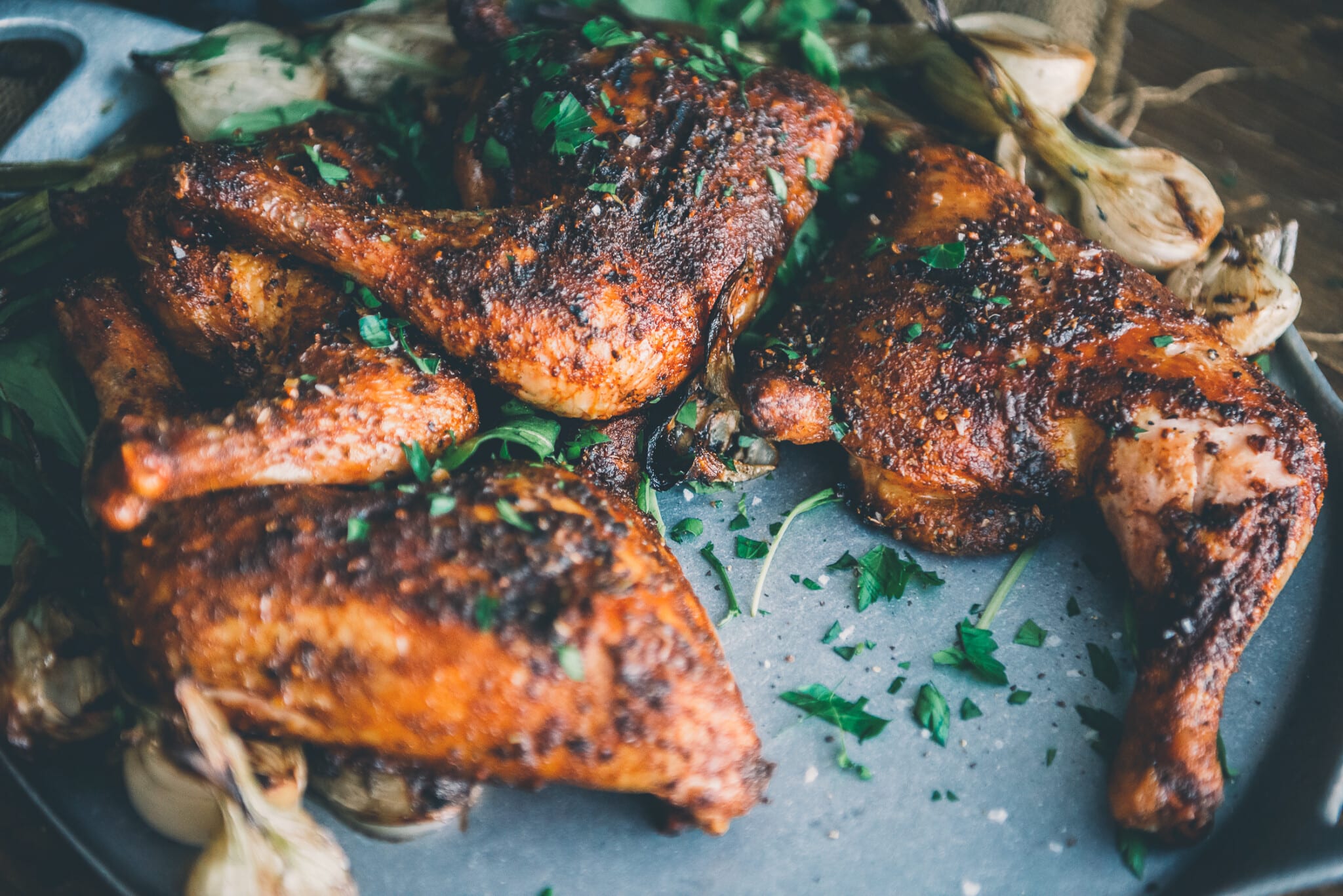 Smoked chicken quarters piled onto a platter. 