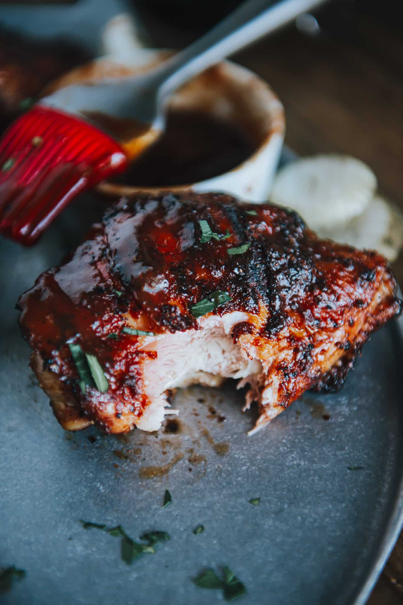 Close up of a smoked chicken thigh with a bite taken out of it.