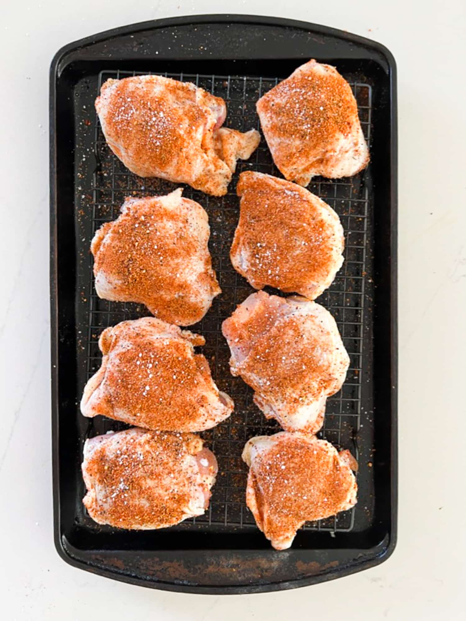 Raw chicken thighs coated with spices.