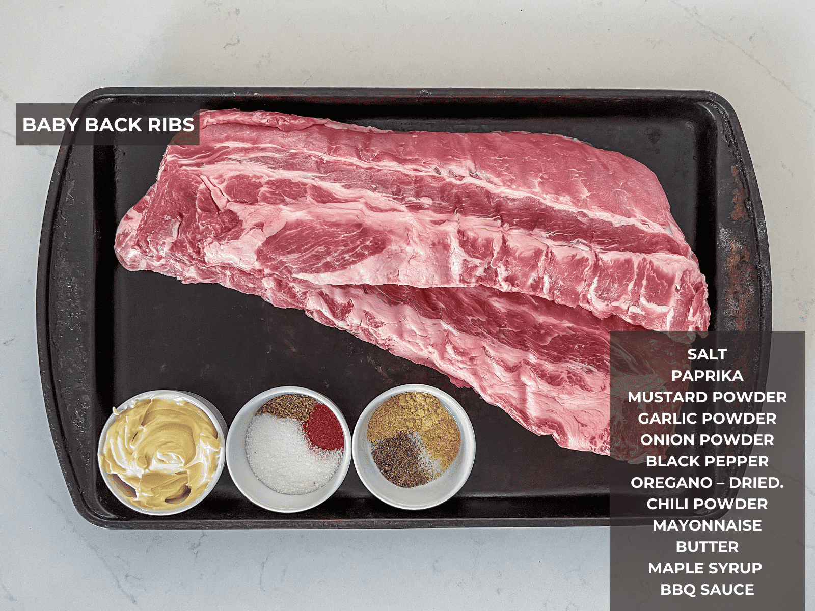 Ingredients for baby back ribs set out on a baking sheet.