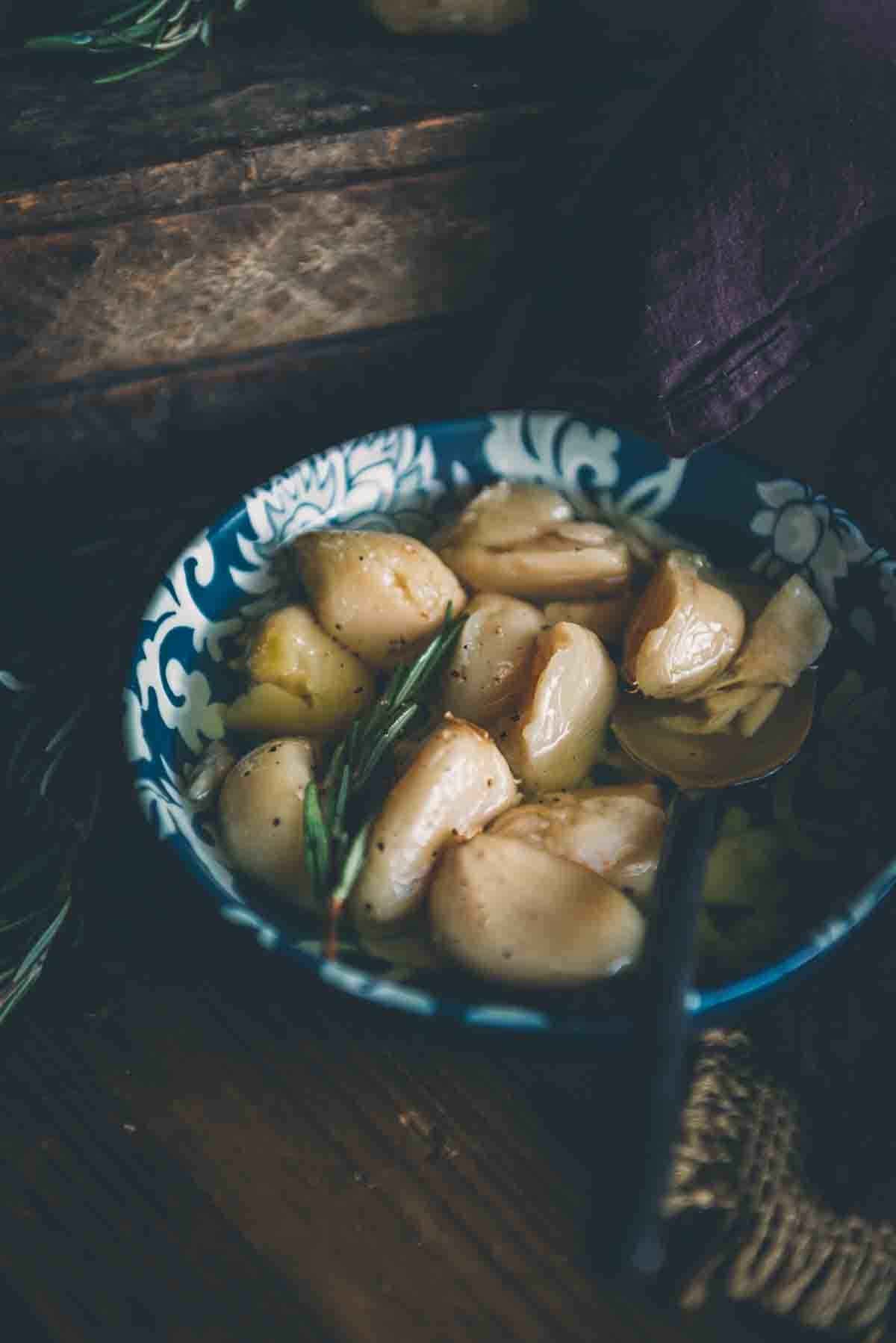 Bowl of smoked garlic confit with rosemary.
