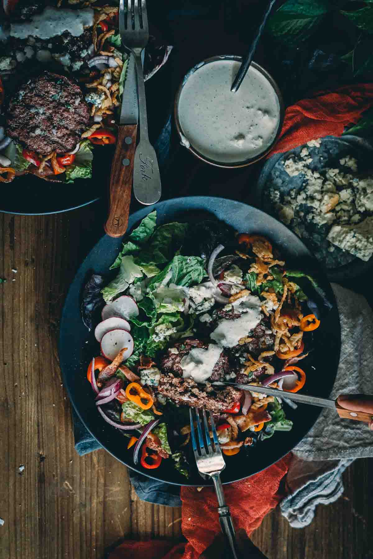 Smoked hamburger patties sliced presented over salad with veggies. 