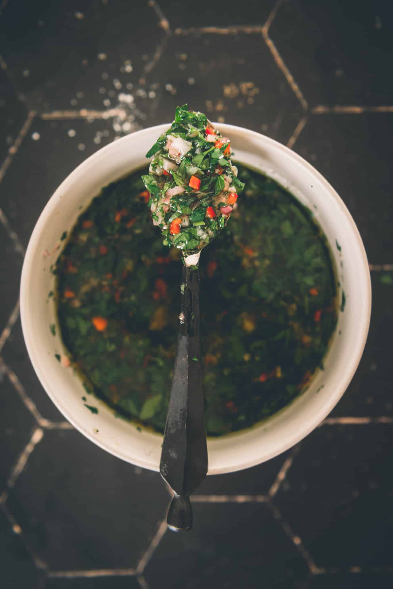 Spoon resting over bowl of chimichurri.