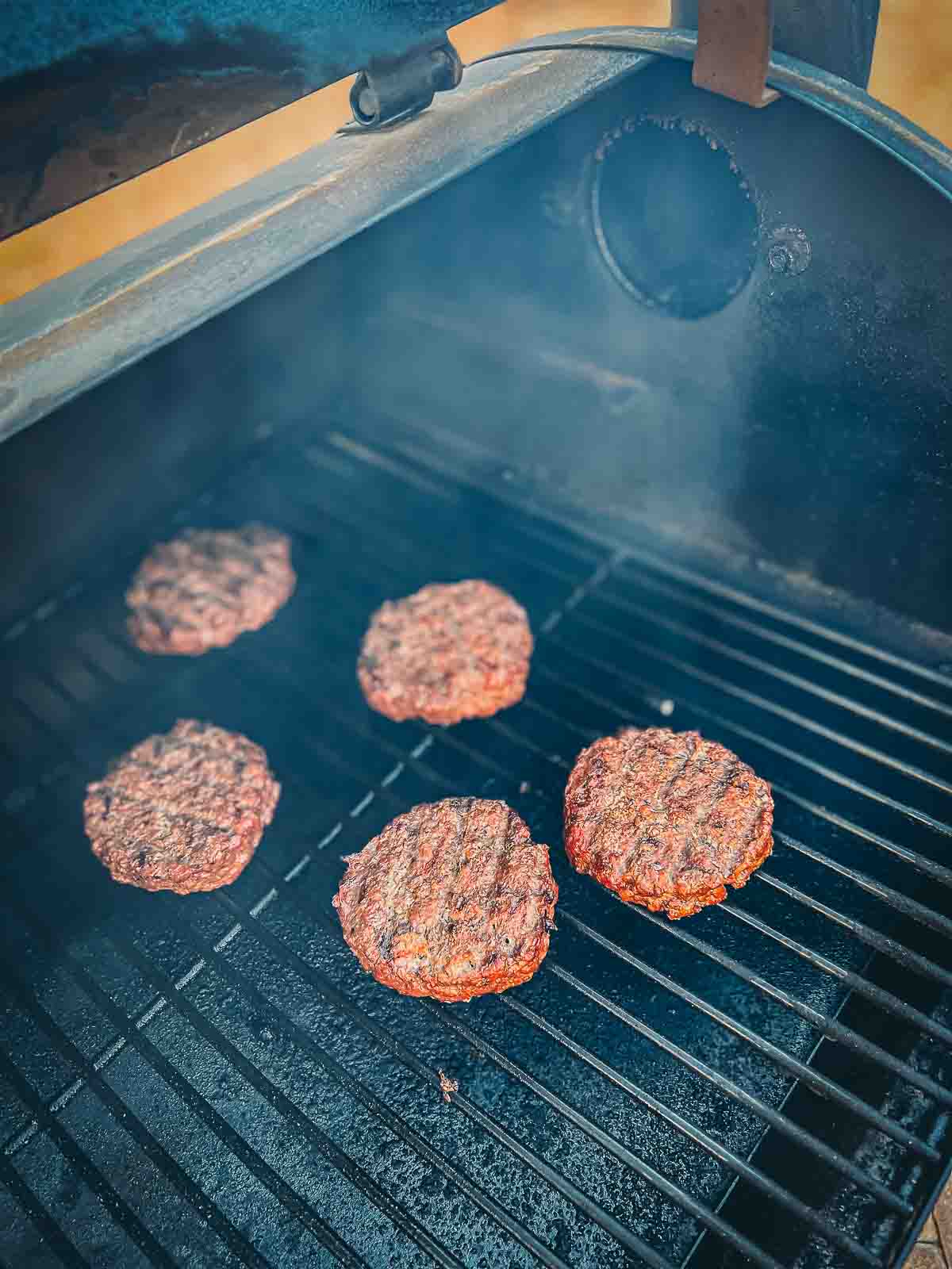 Ground beef patties being smoked on a pellet grill. 