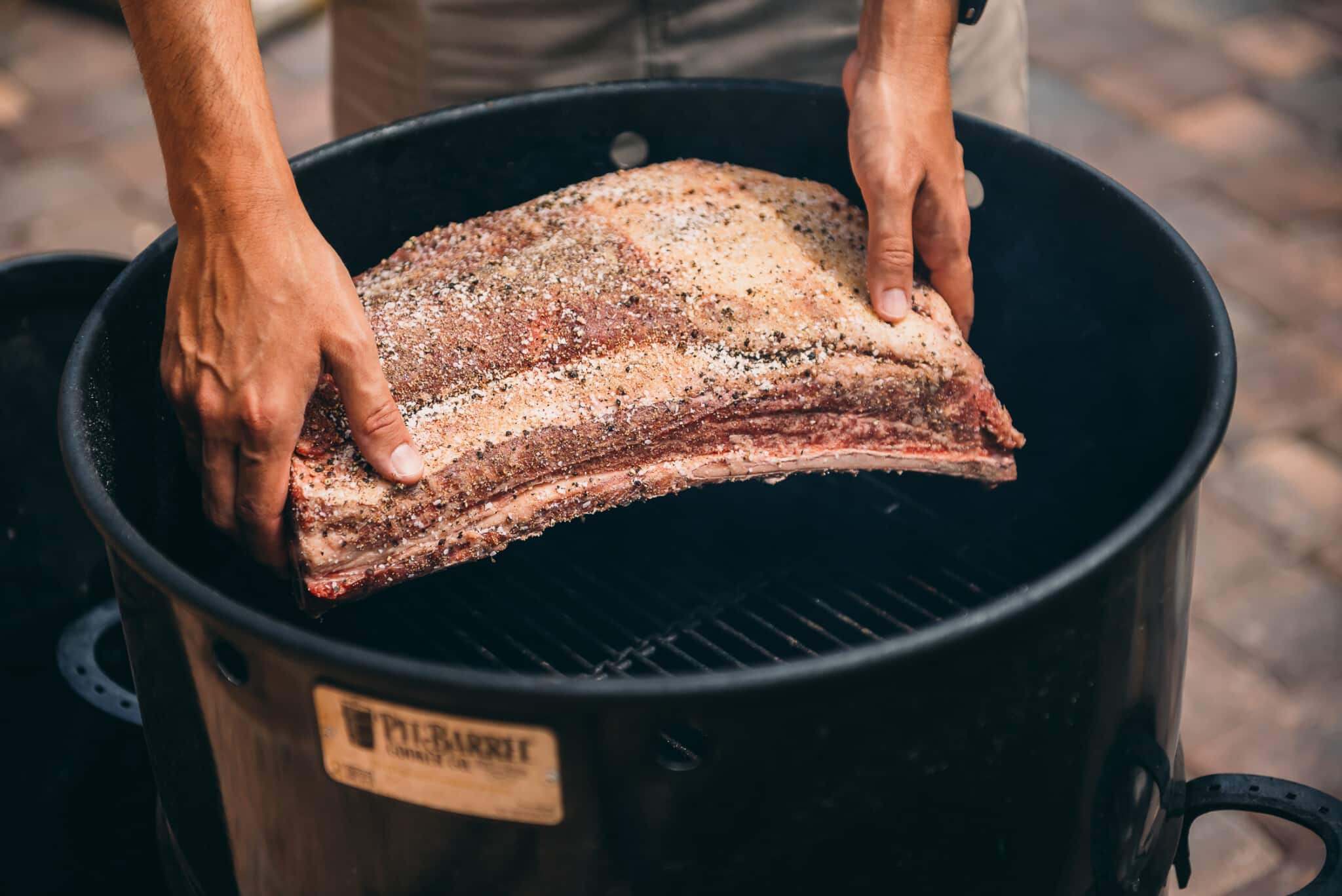 Beef ribs being placed in a smoker.