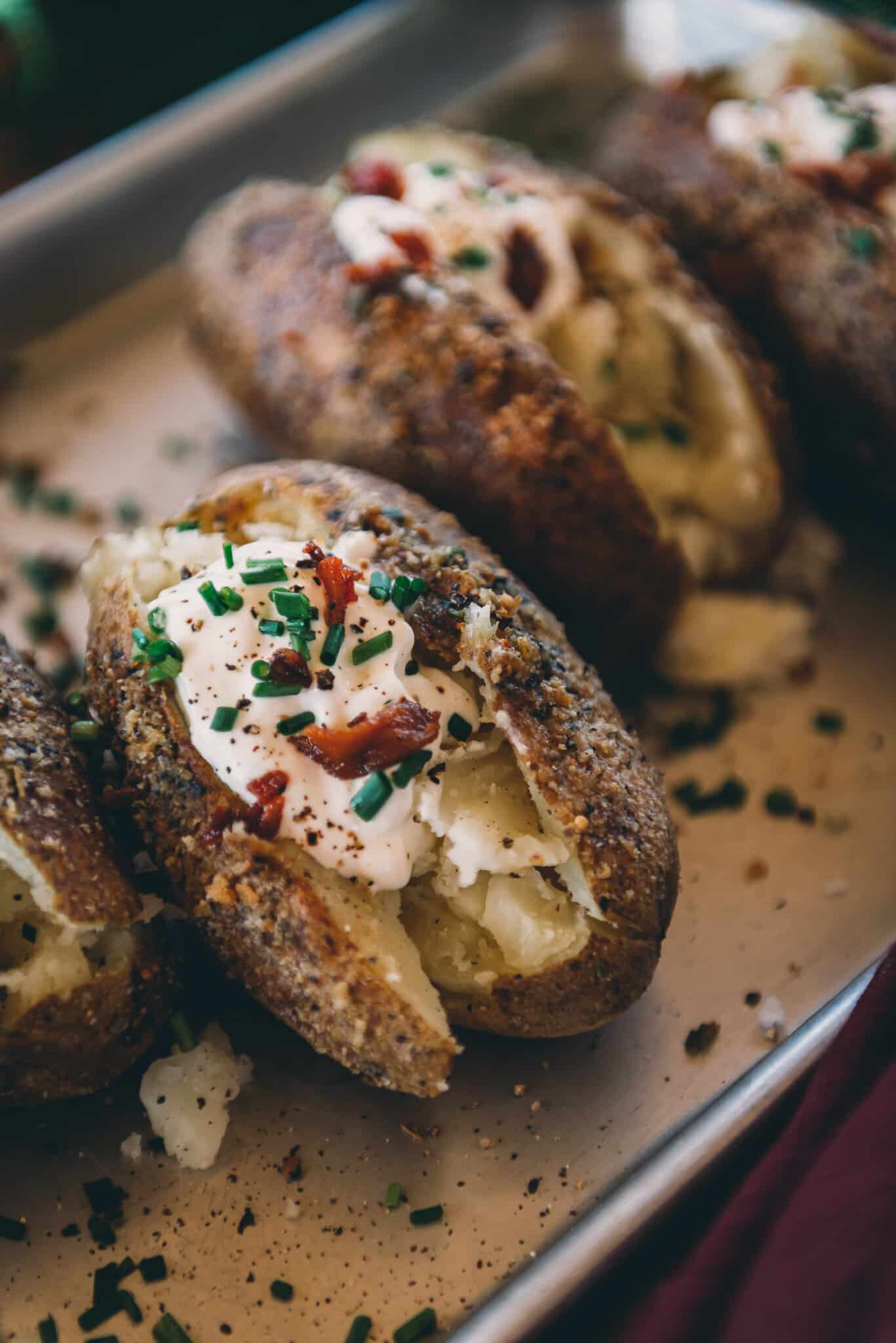 TAight shot of a russet potato that was smoked for crispy herb crusted skin, flaky flesh and toppings piled on top. 