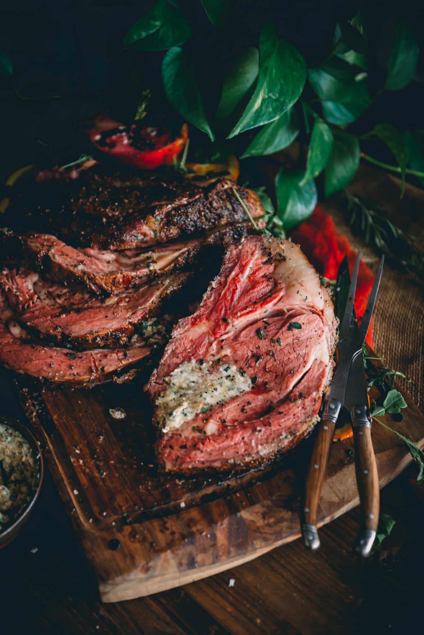 Close up of sliced smoked prime rib beef on a cutting board with herb butter.