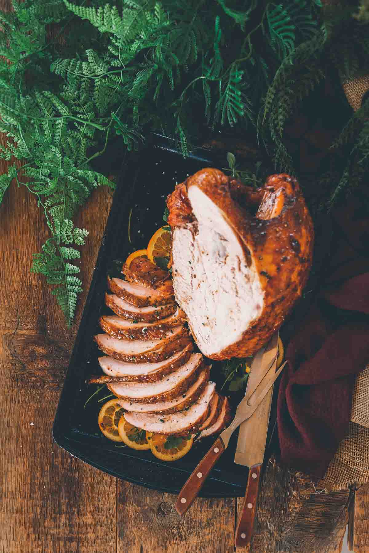 Overhead shot of bone in turkey breast smoked and one half carved arranged on a platter. 