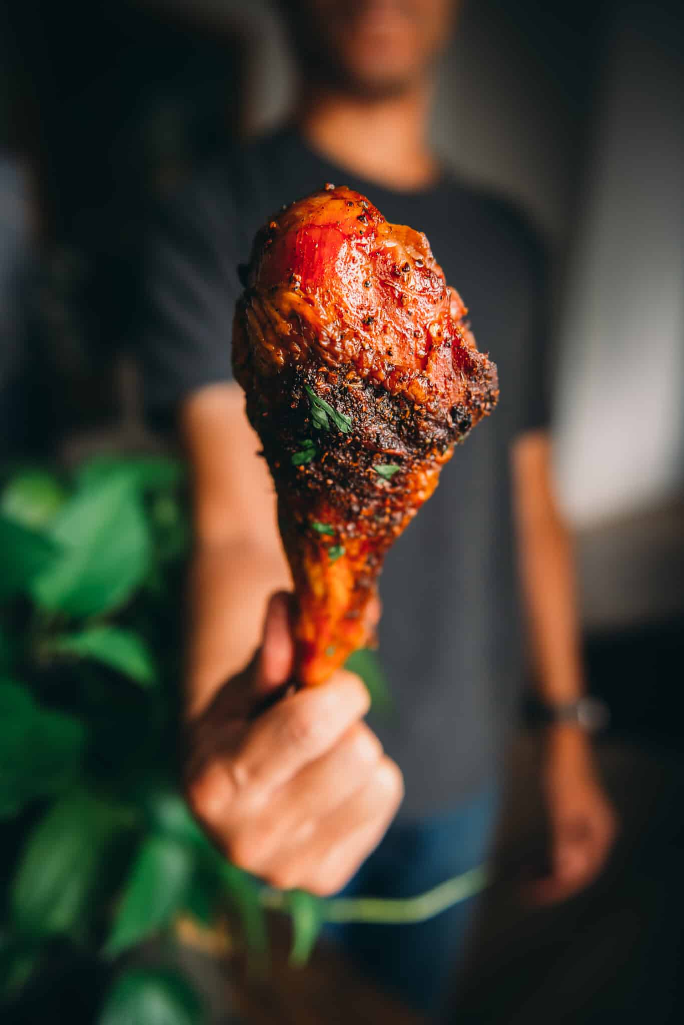 Hand holding smoked turkey leg out to camera. 