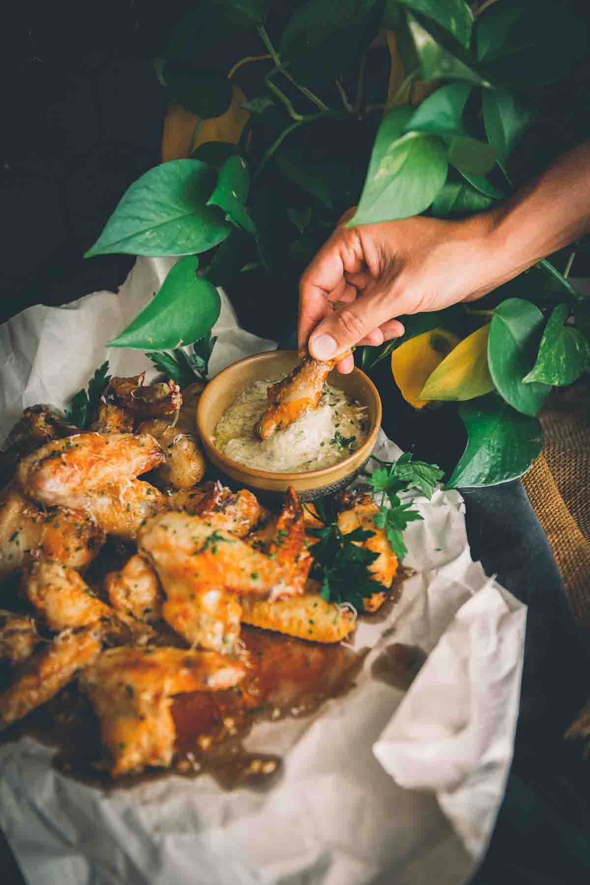 Hand dipping wing into garlic parm wing sauce.