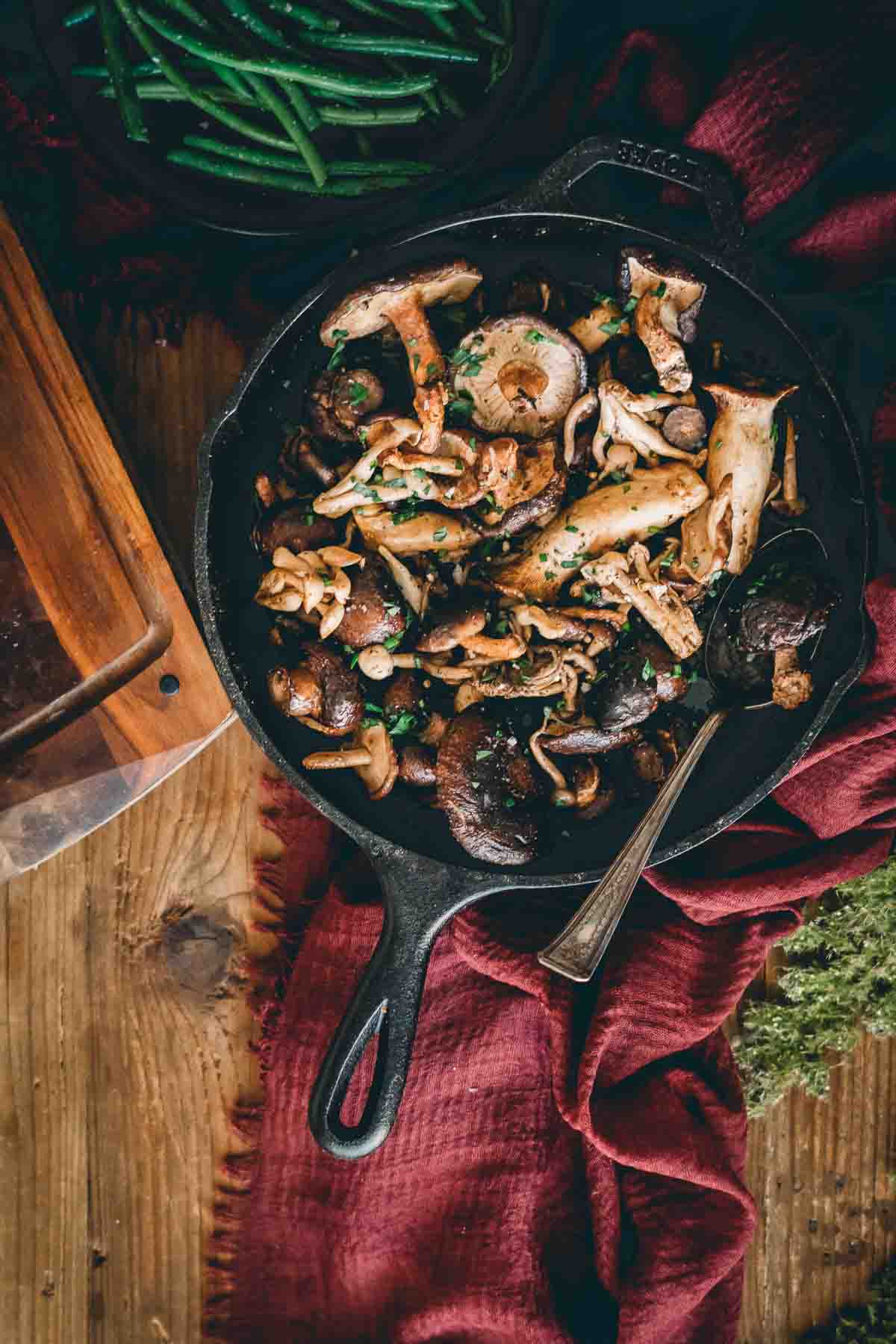 Overheat shot of cast iron skillet filled with cooked mushrooms. 