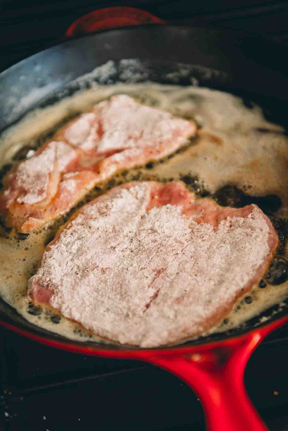 Veal cutlets in frying pan.