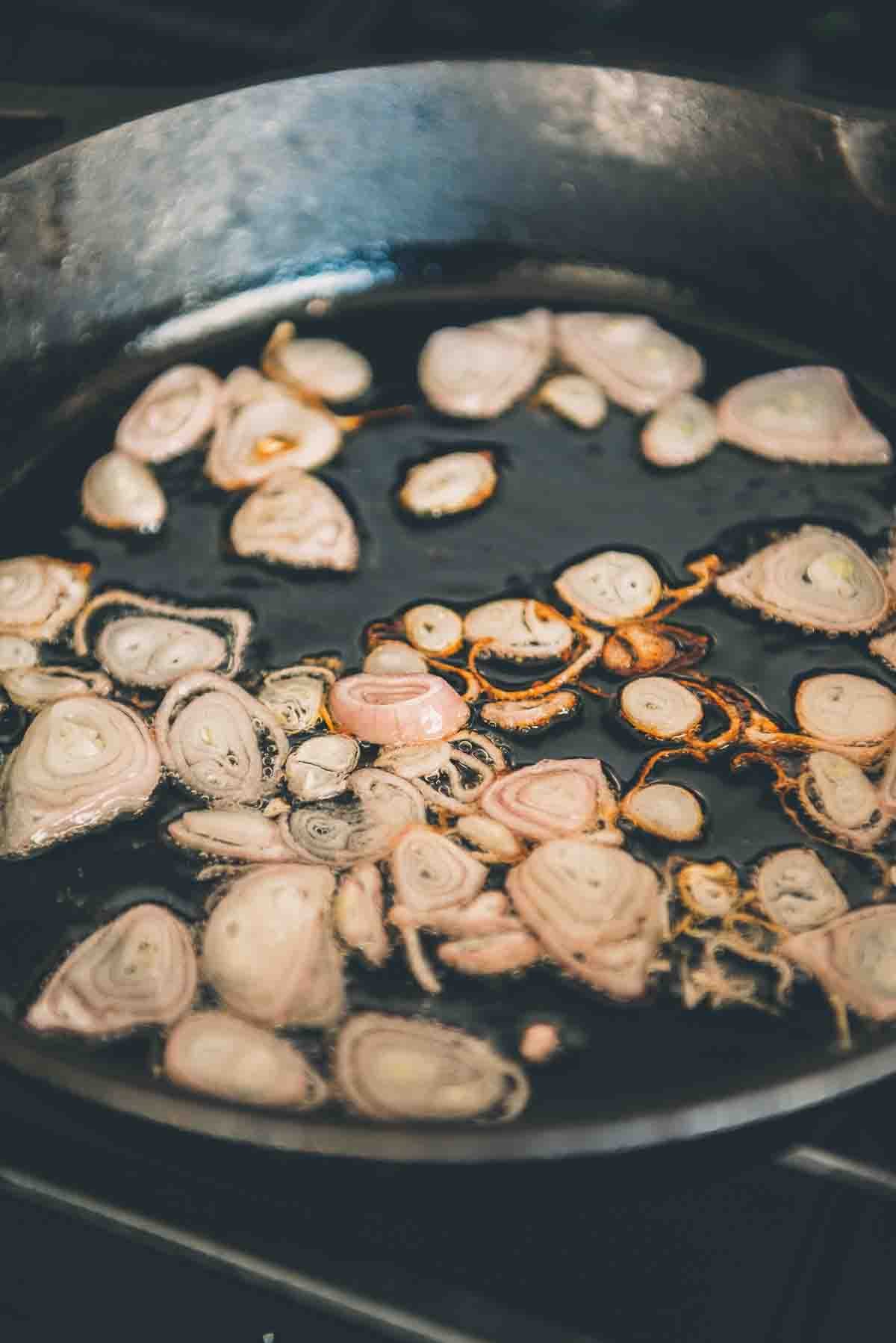 Shallots frying in a pan.