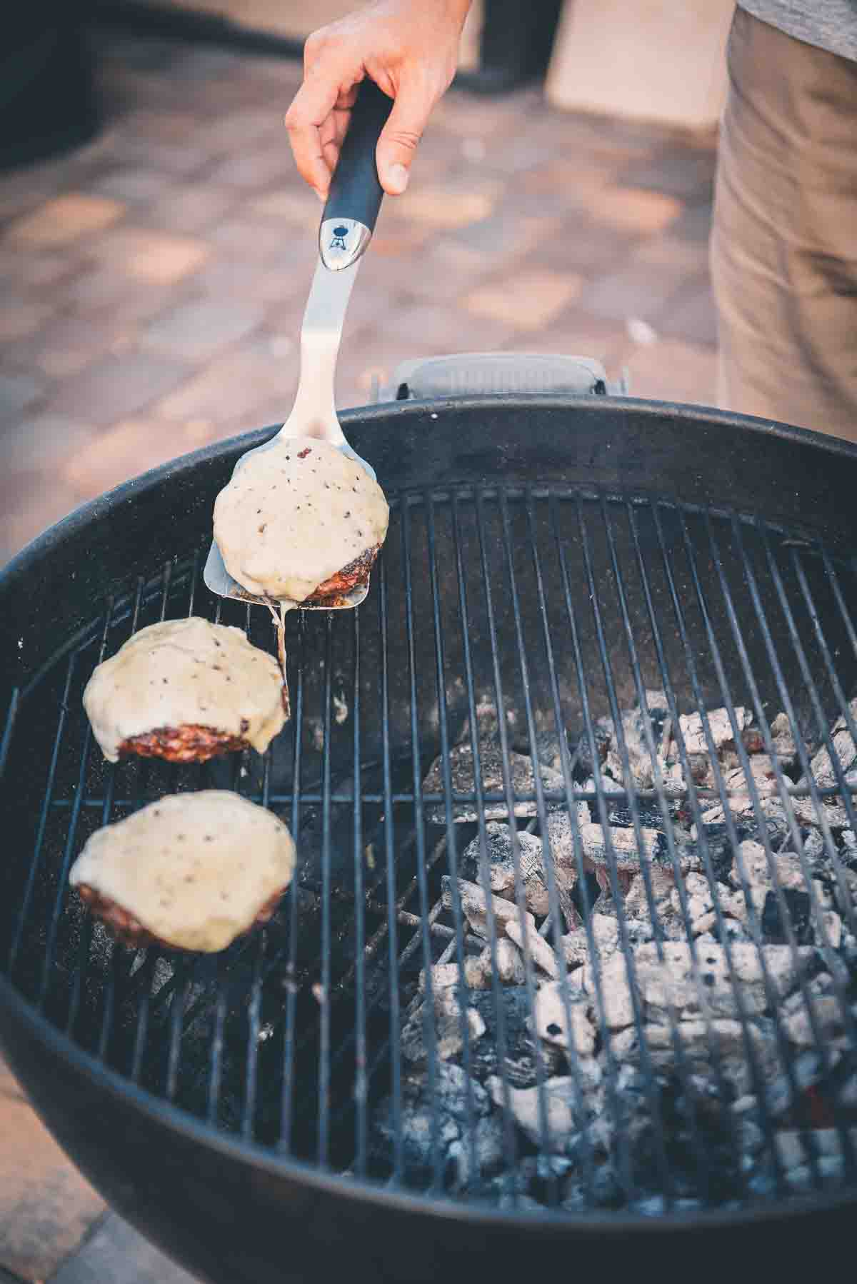 Cheesy burgers coming off the grill.