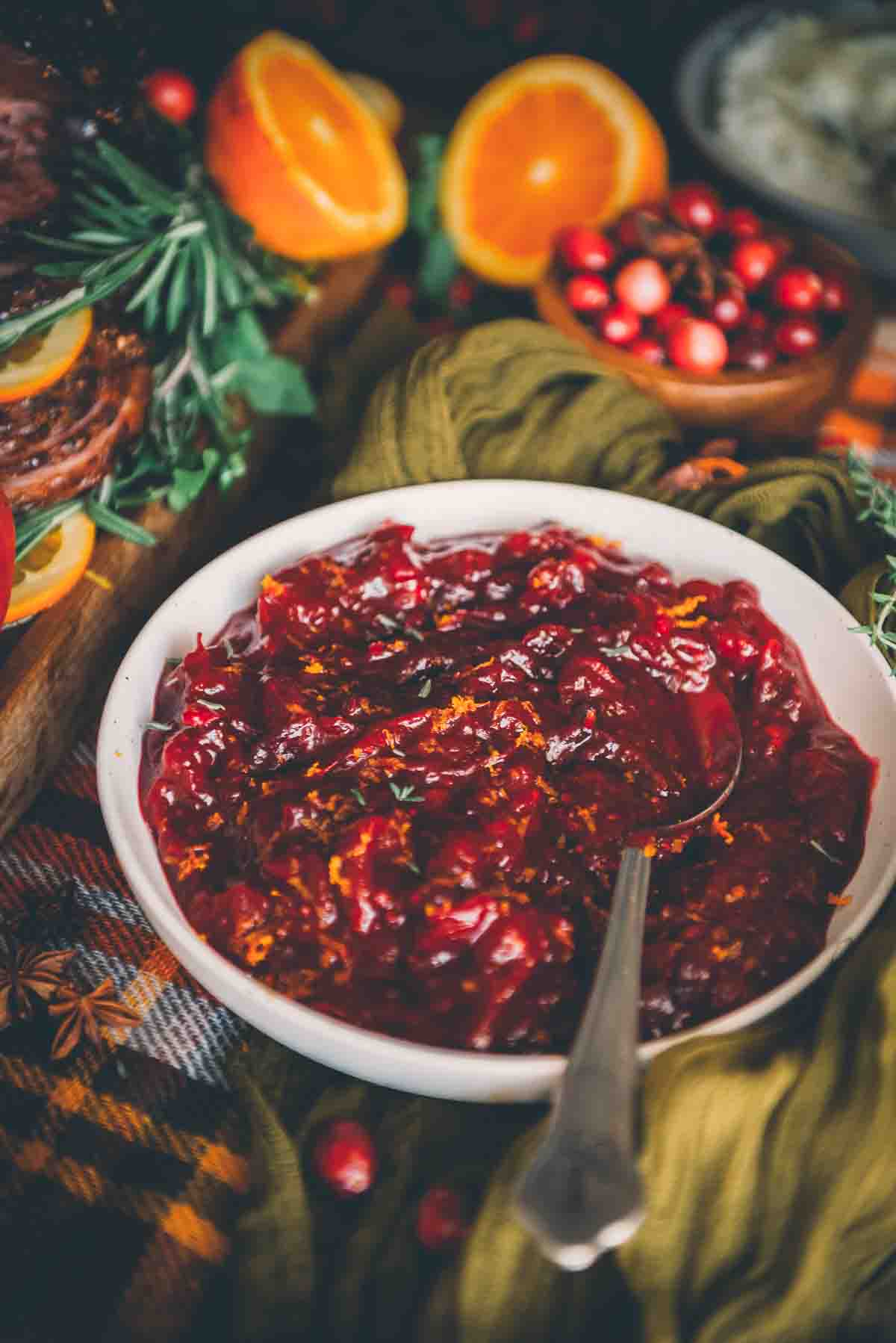 Close up of beautiful red cranberry sauce garnished with orange zest and thyme leaves.