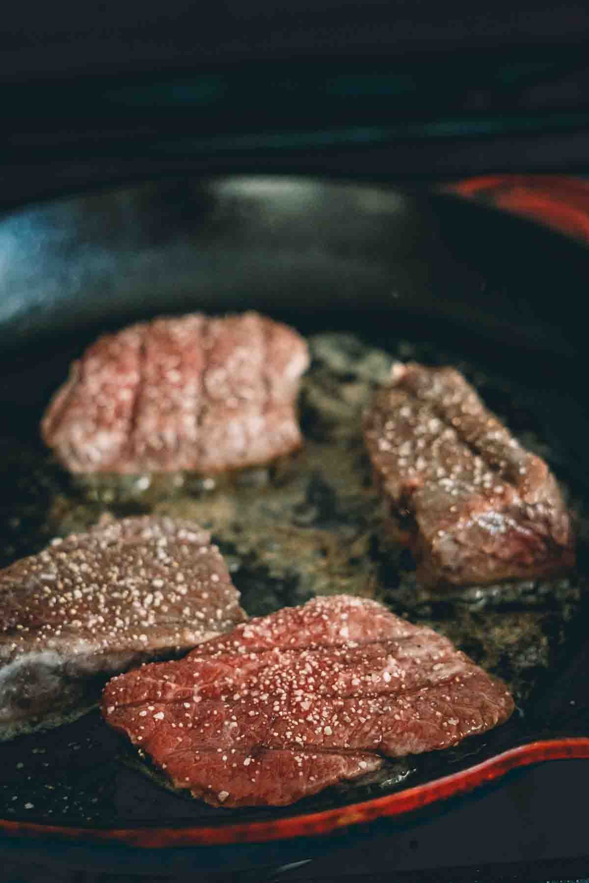 Venison steaks in a cast iron skillet. 