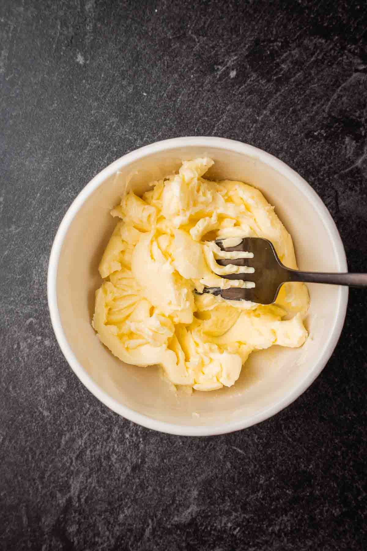 Butter mashed with a fork in a white bowl.