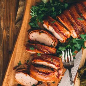 Sliced smoked pork loin on a wooden cutting board.