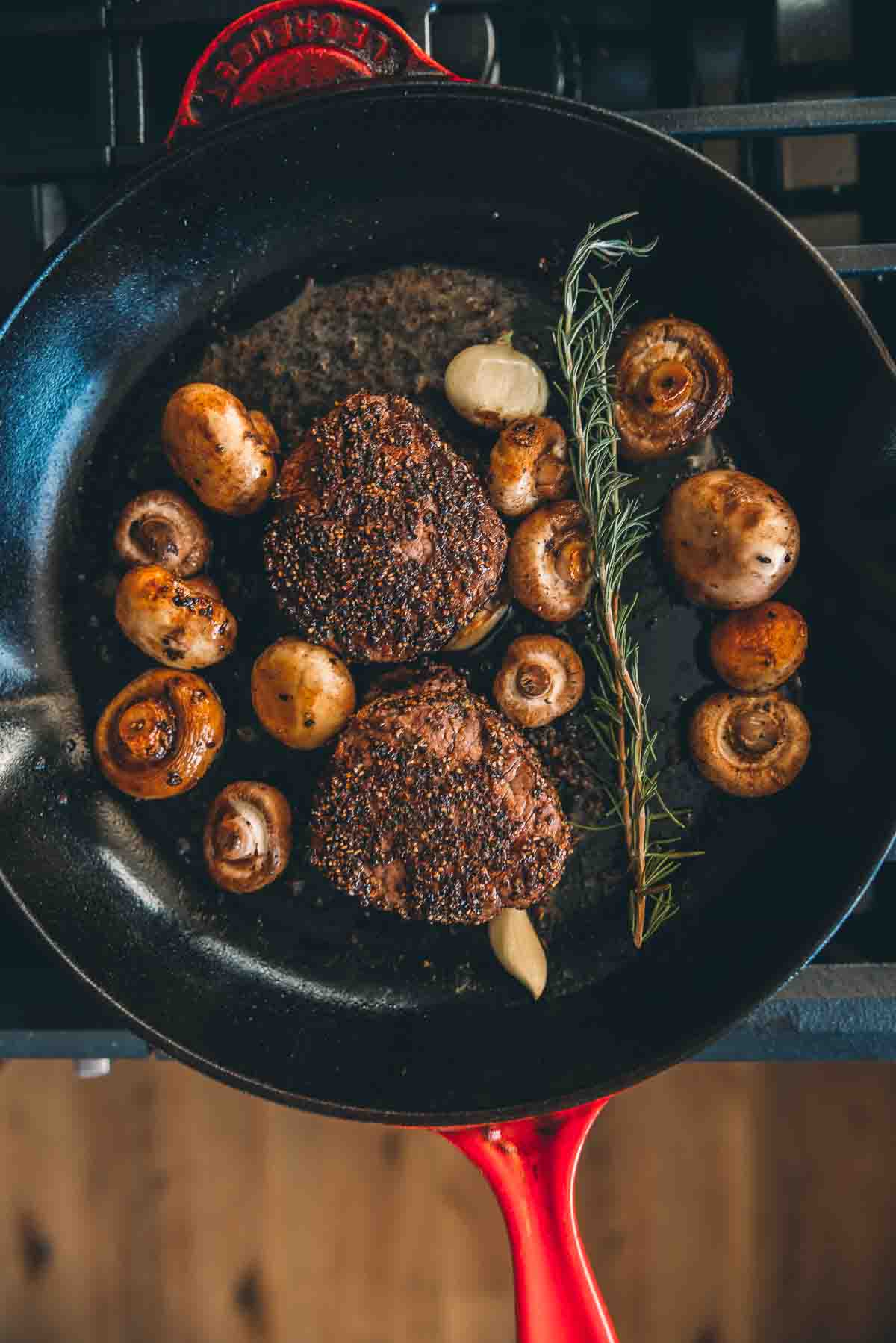 Seared filets in a skillet with mushrooms, butter, rosemary and garlic. 