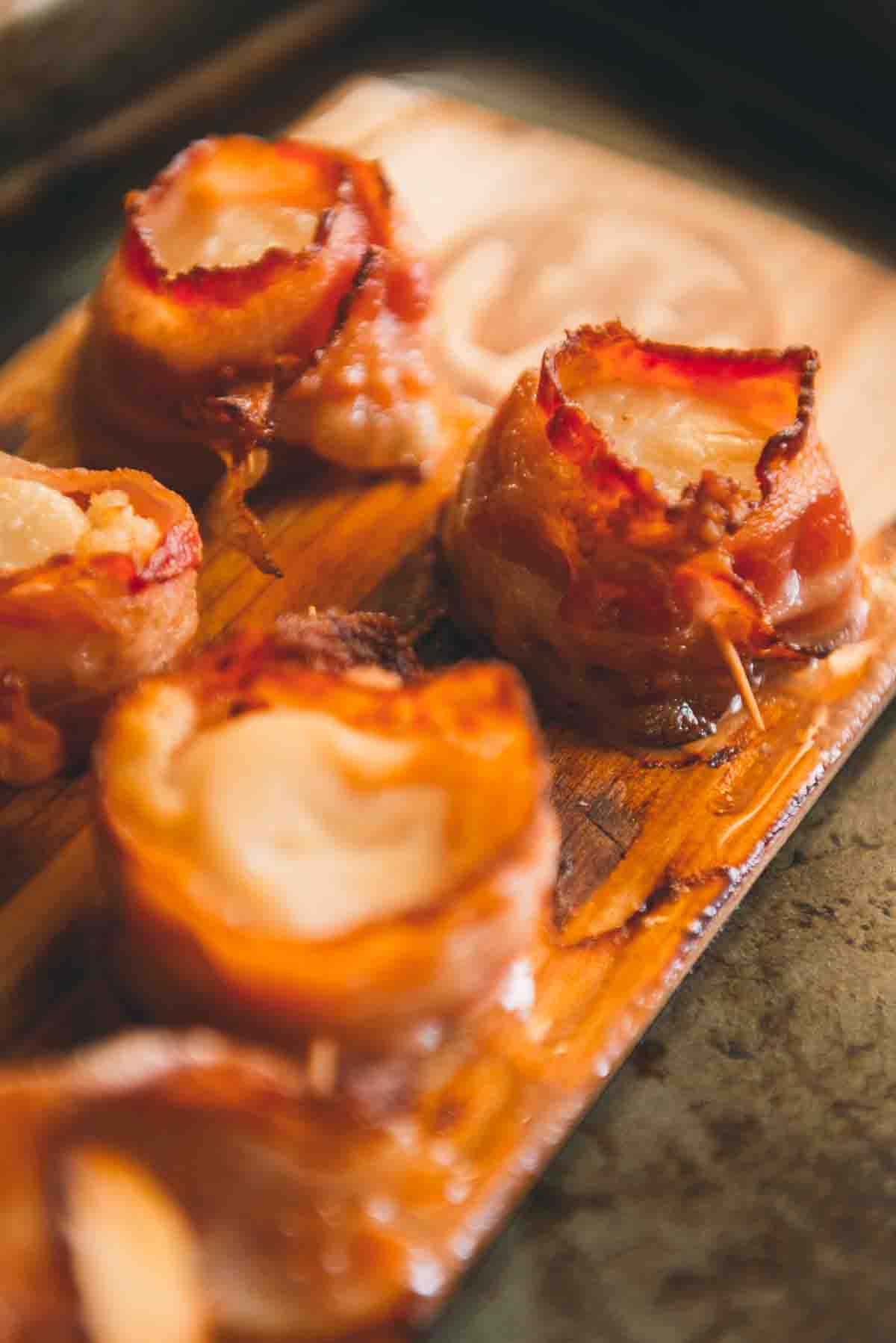Close up side shot of cooked scallops to show crispy bacon.