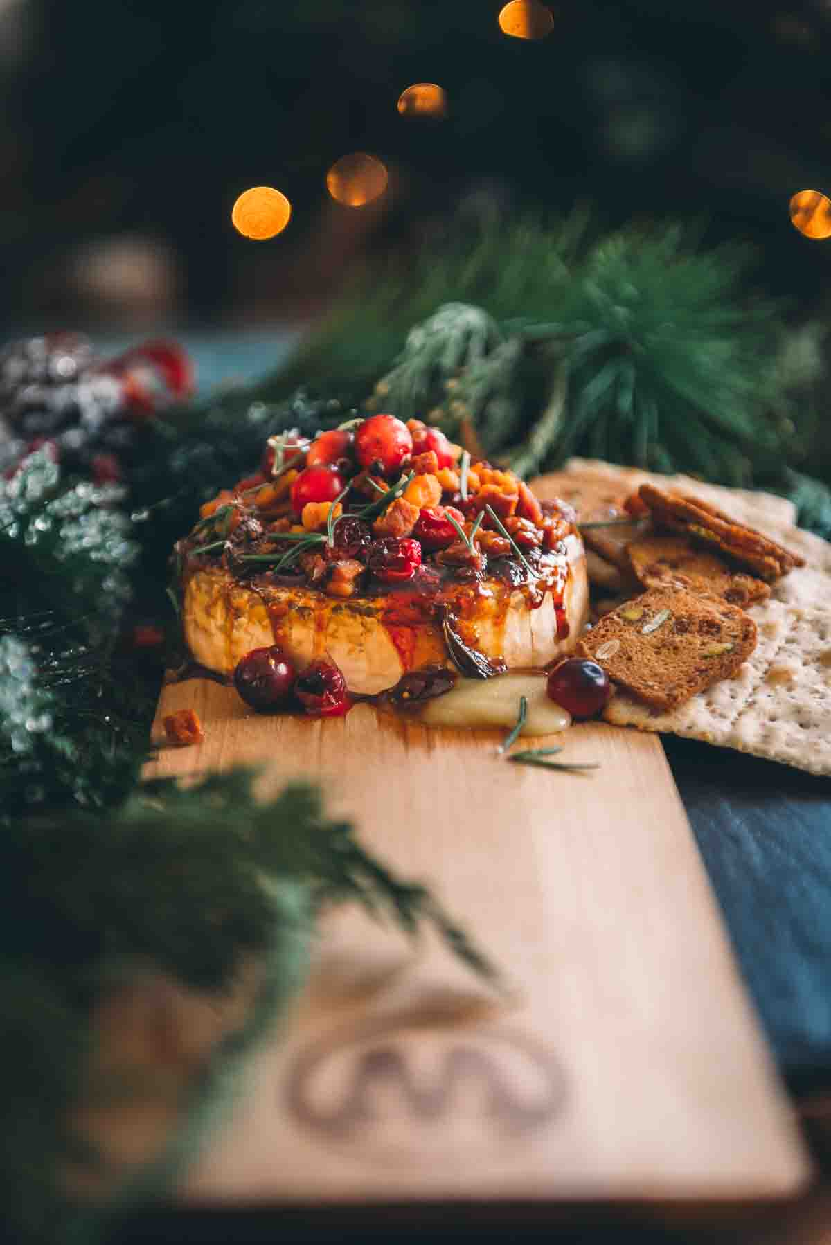 Shallow focus image of this appetizer recipe on a wooden smoking plank with crackers around it for serving. 