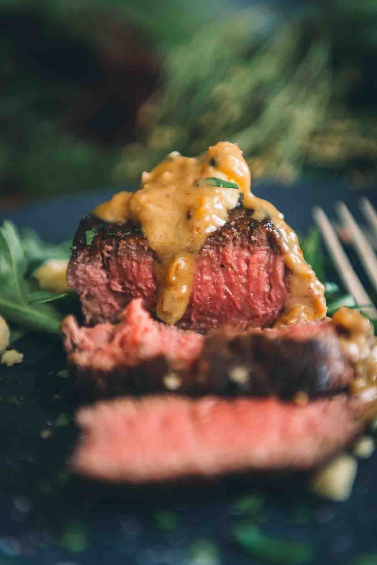Close up of perfectly cooked steak and rich creamy blue cheese sauce over top. 