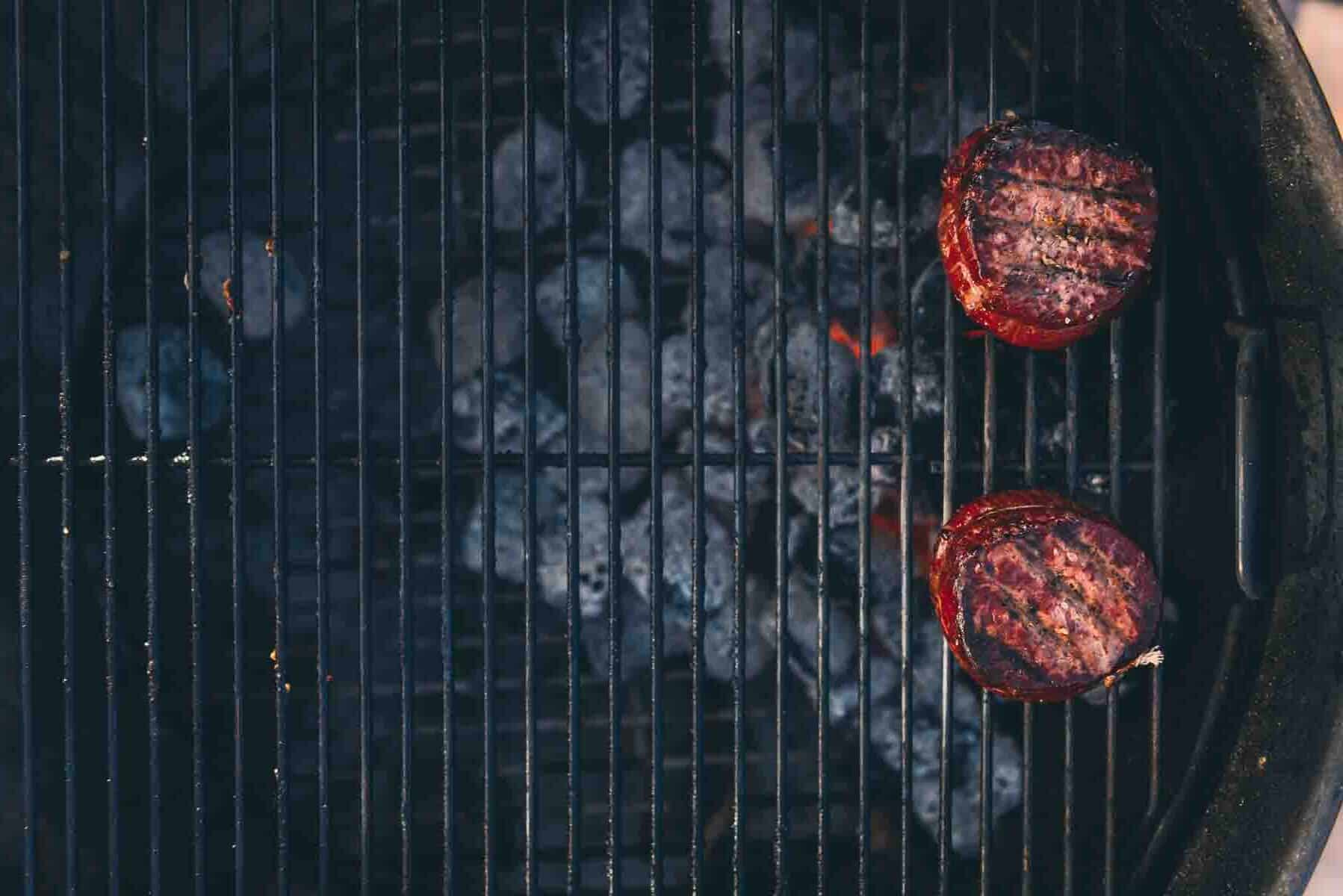 Overhead shot shoring steaks directly over the coals, the direct heat, for a 2 zone fire.
